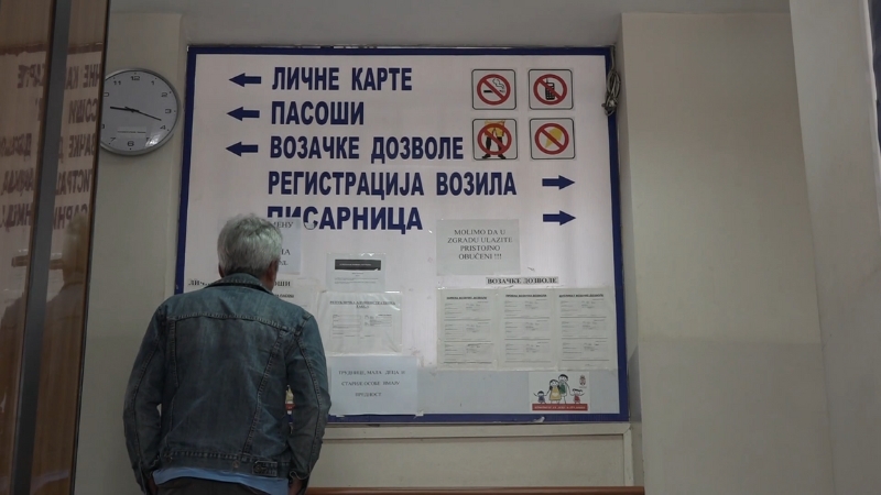 Muškarac stoji ispred informativne table u upravnoj zgradi