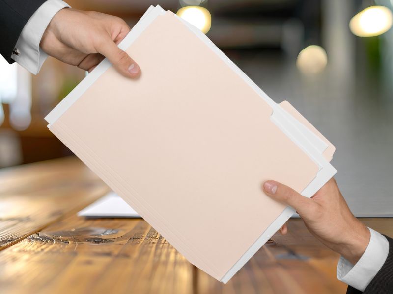 osoba predaje drugoj osobi fasciklu sa dokumentima