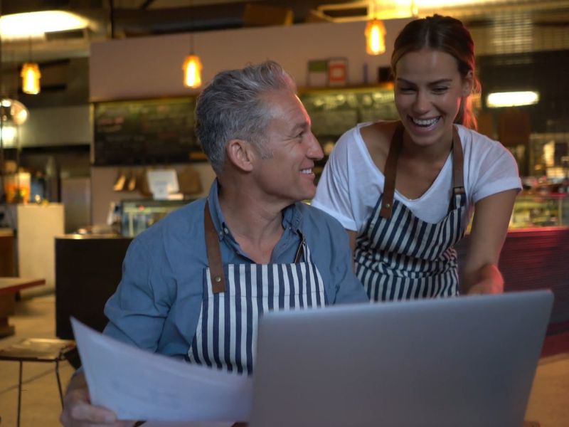 vlasnik restorana i devojka proveravaju finansije restorana uz smeh