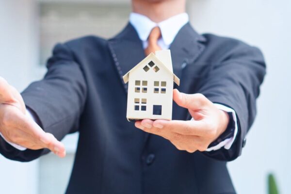 osoba pokazuje rukom na kuću, simulirajući na kupoprodaju stana