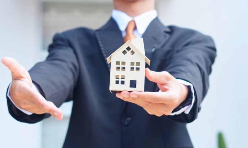 osoba pokazuje rukom na kuću, simulirajući na kupoprodaju stana