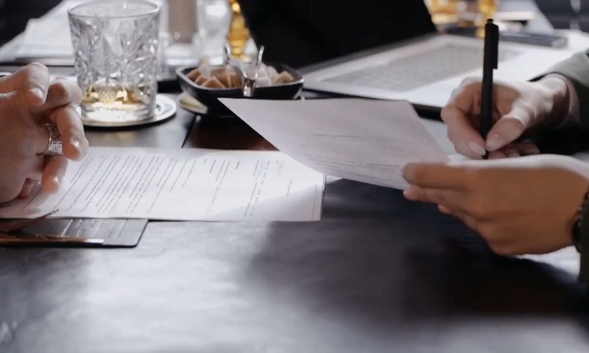 osoba pokazuje drugoj osobi ugovor o kupoprodaji stana i gde treba da potpiše