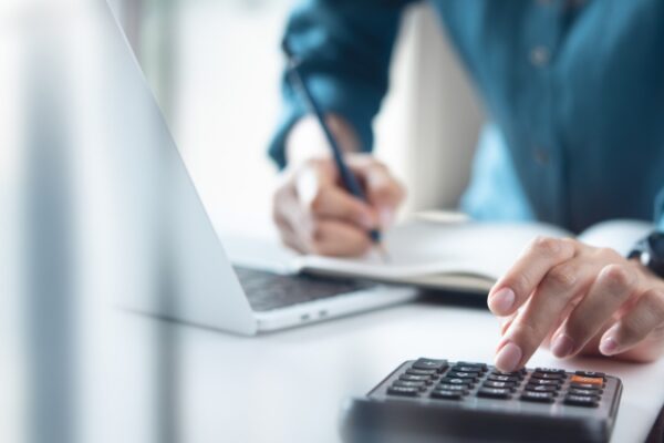 Knjigovođa za radnim stolom koristi kalkulator i laptop