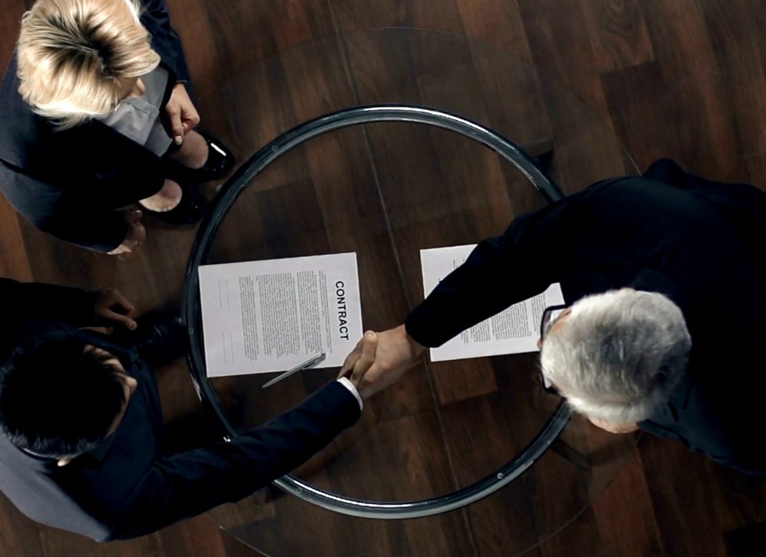 osobe se rukuju nakon potpisivanja dokumenata.