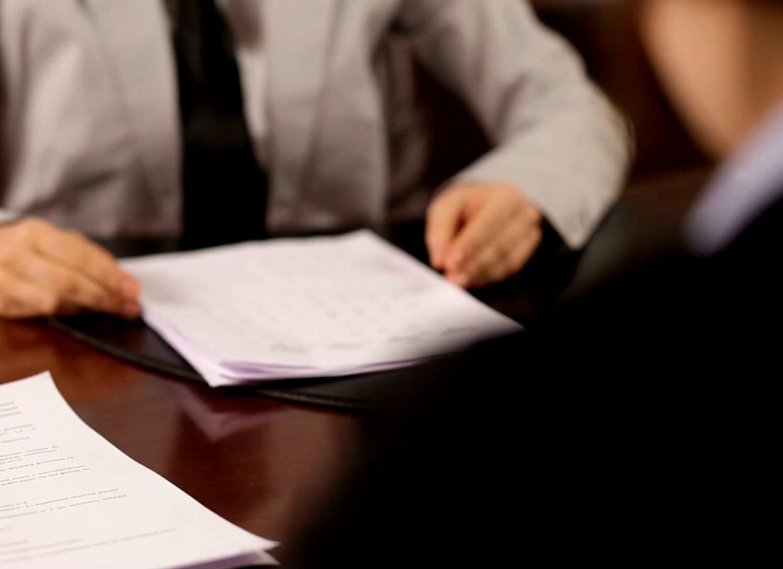 osobe sede za stolom i gledaju u papire