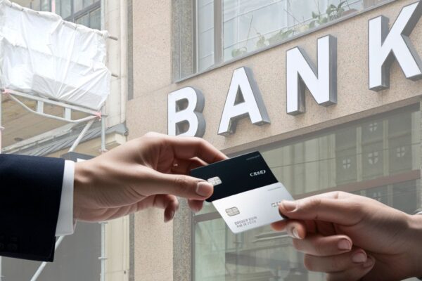 dve osobe međusobno daju jedna drugoj bankovne kartice, banka u pozadini