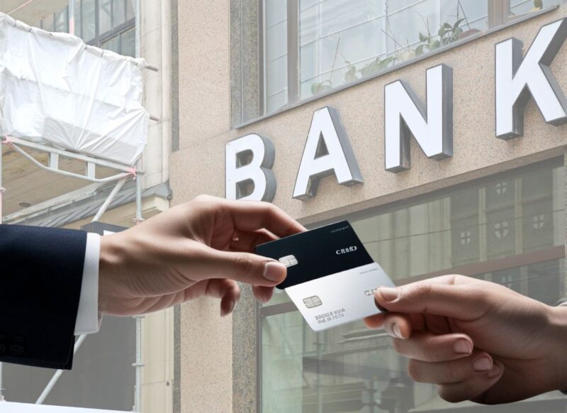 dve osobe međusobno daju jedna drugoj bankovne kartice, banka u pozadini