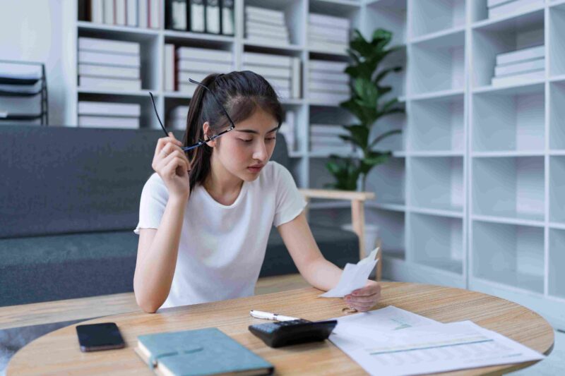 Žena proverava račun i dokumenta za stolom sa kalkulatorom
