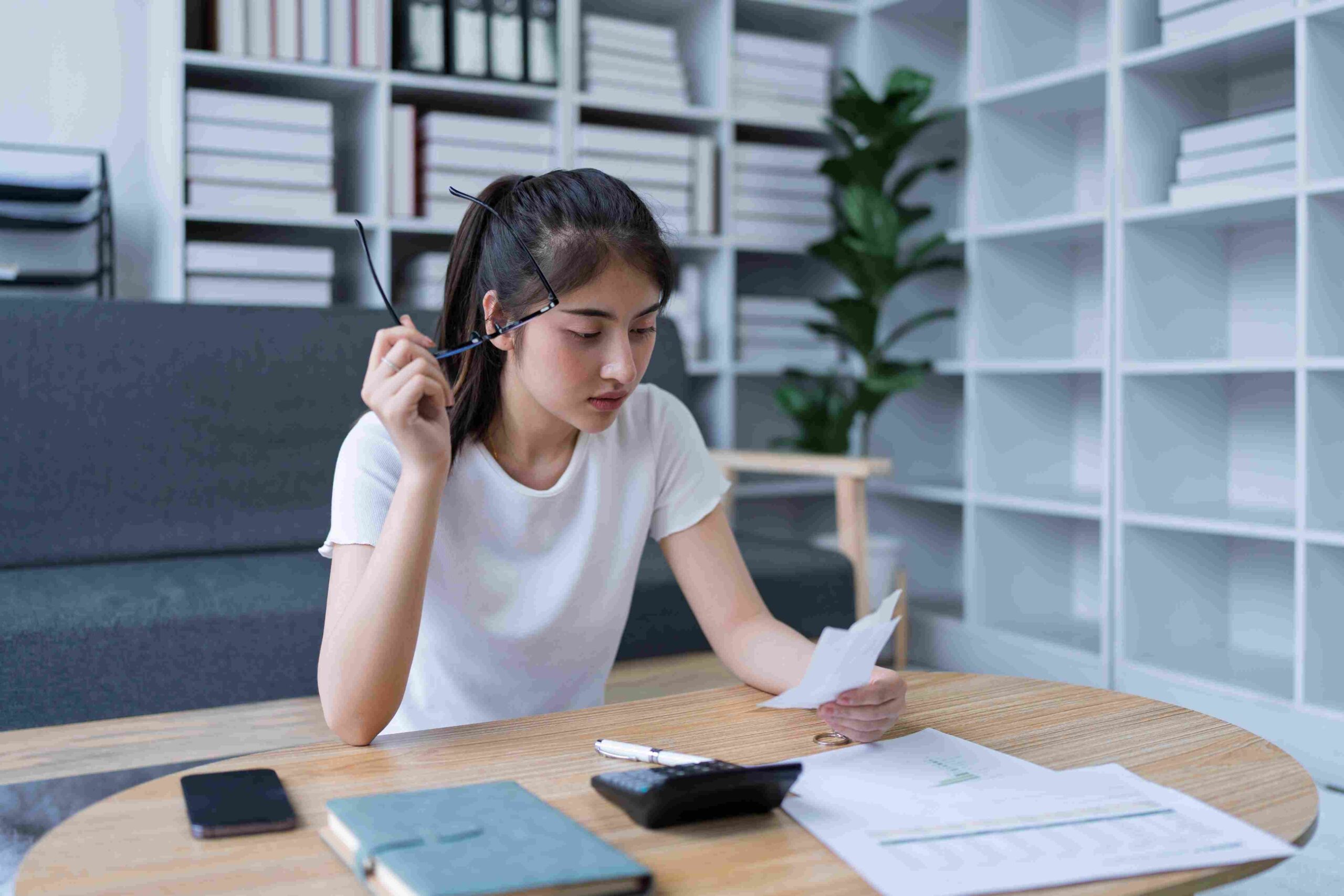 Žena proverava račun i dokumenta za stolom sa kalkulatorom