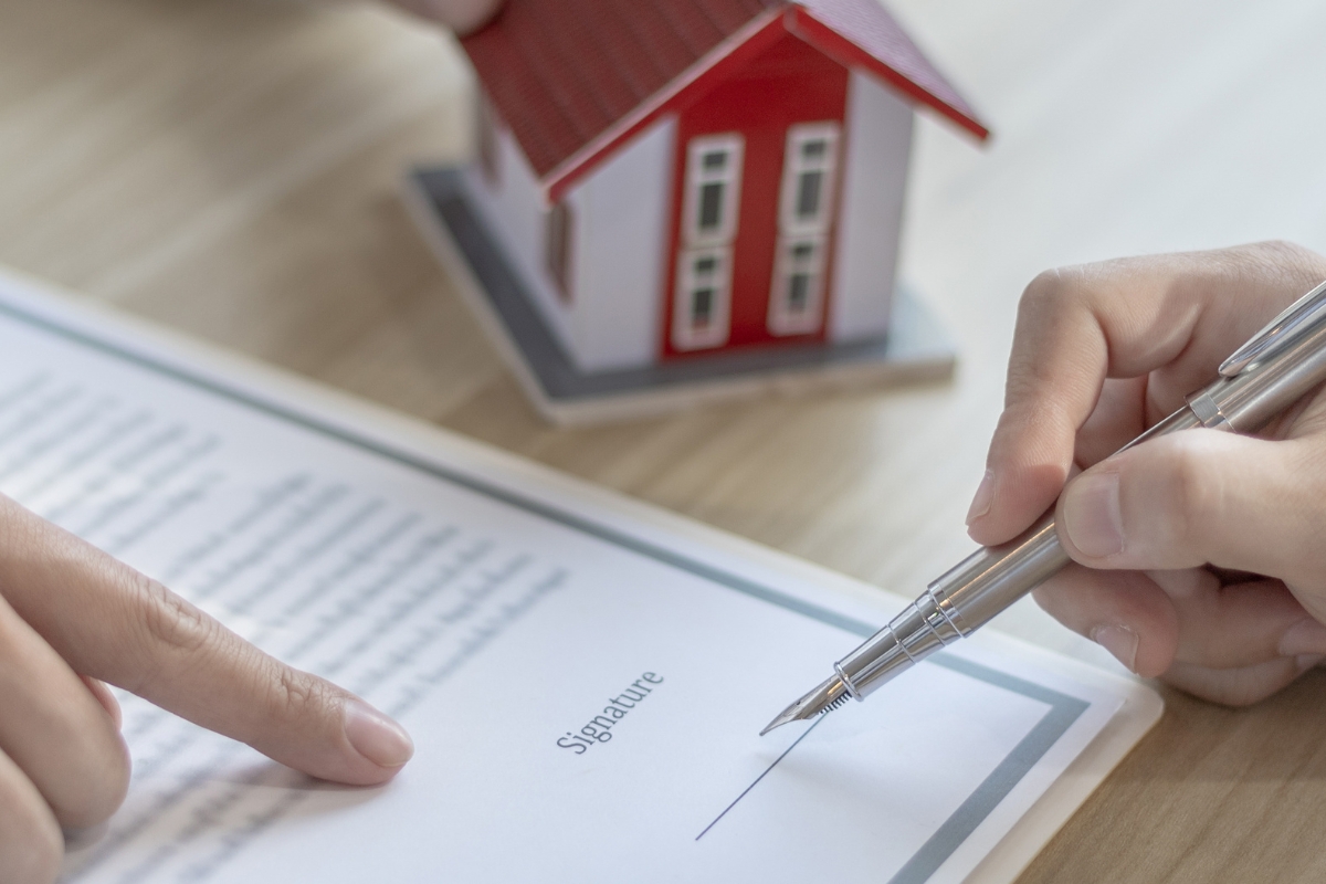 osoba potpisuje papire za prenos vlasništva stana